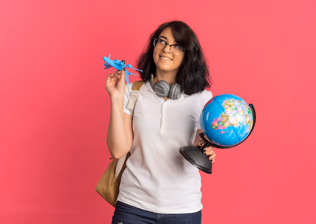 young-pleased-pretty-caucasian-schoolgirl-with-headphones-neck-wearing-glasses-back-bag-holds-plane-globe-looking-up-pink-with-copy-space_141793-62632